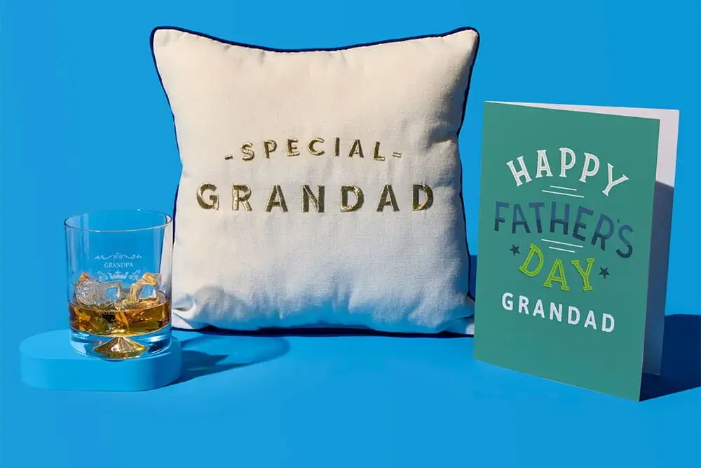 Fathers Day gift set on a blue background featuring a Special Grandad cushion, a whisky glass, and a Happy Fathers Day Grandad card